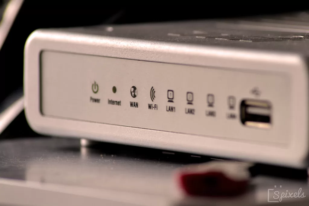 Ezüst színű router előlapja a tápellátás, internet, WAN, Wi-Fi és LAN jelzőfényekkel